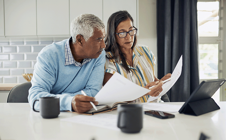 Senior couple at table looking at retirement planning financial documents