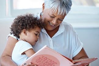 Grandmother reading a book to a grandchild on her lap