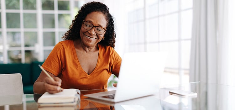 Single senior woman writing in a gratitude journal as part of her wellness resolution