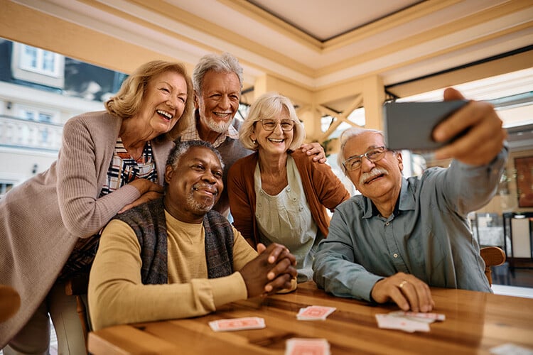 Diverse group of 5 senior friends laughing and taking a selfie