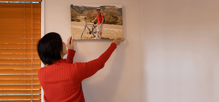 Woman in red sweater hanging a family photo on wall