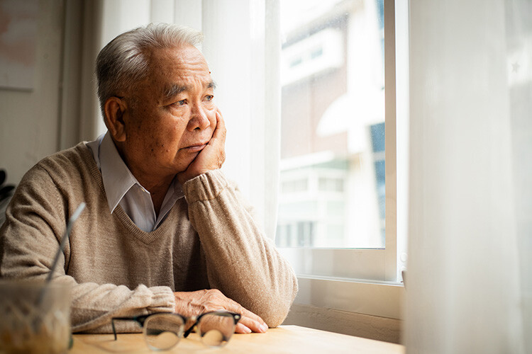 Older man staring out window in winter