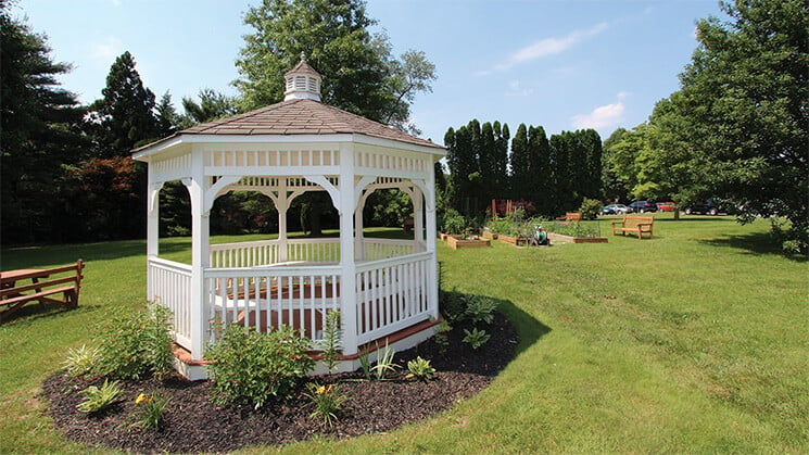 White gazebo with raised garden beds in the backtround