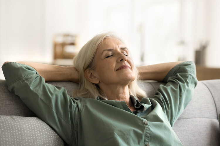 Woman relaxing by leaning back on sofa