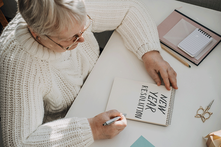 Senior Woman writing out new year resolutions