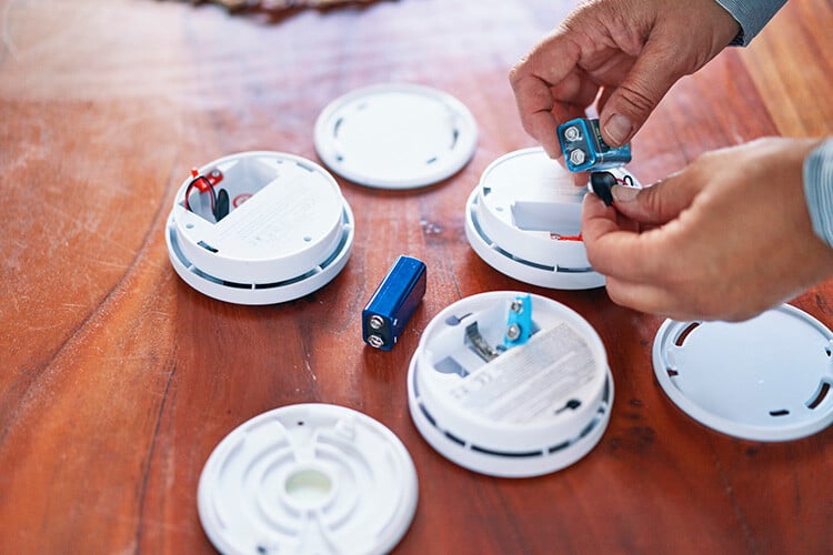 Several open smoke detectors on a table, getting new batteries