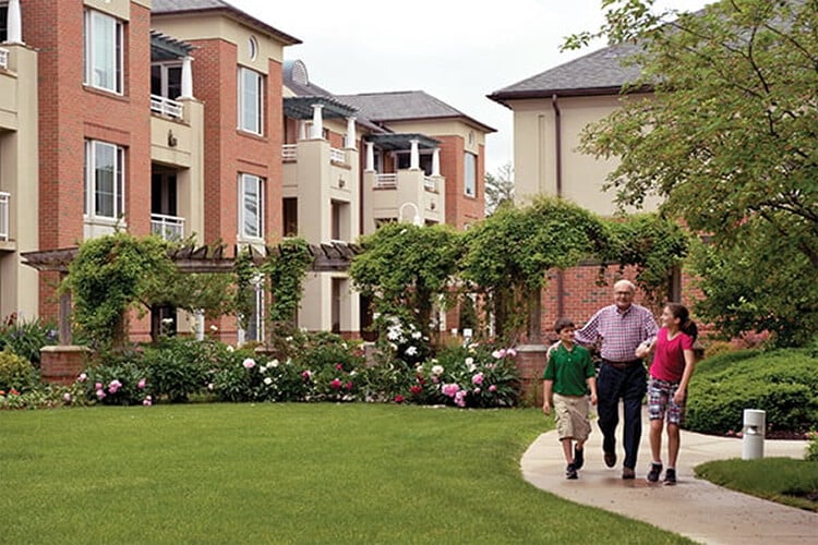 Senior man walking with grandchildren in a senior living community